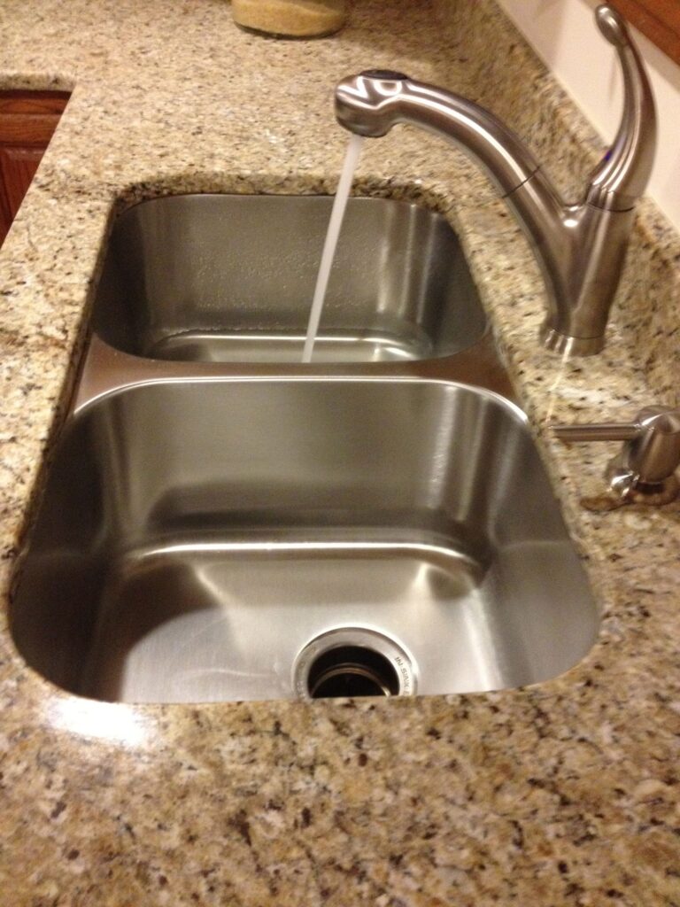 50/50 double bowl stainless steel sink installed in a granite countertop