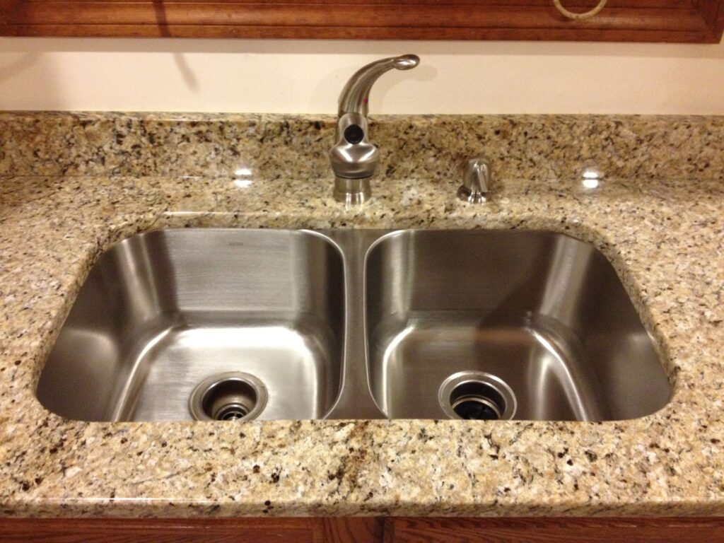 50/50 double bowl stainless steel sink installed under a granite countertop