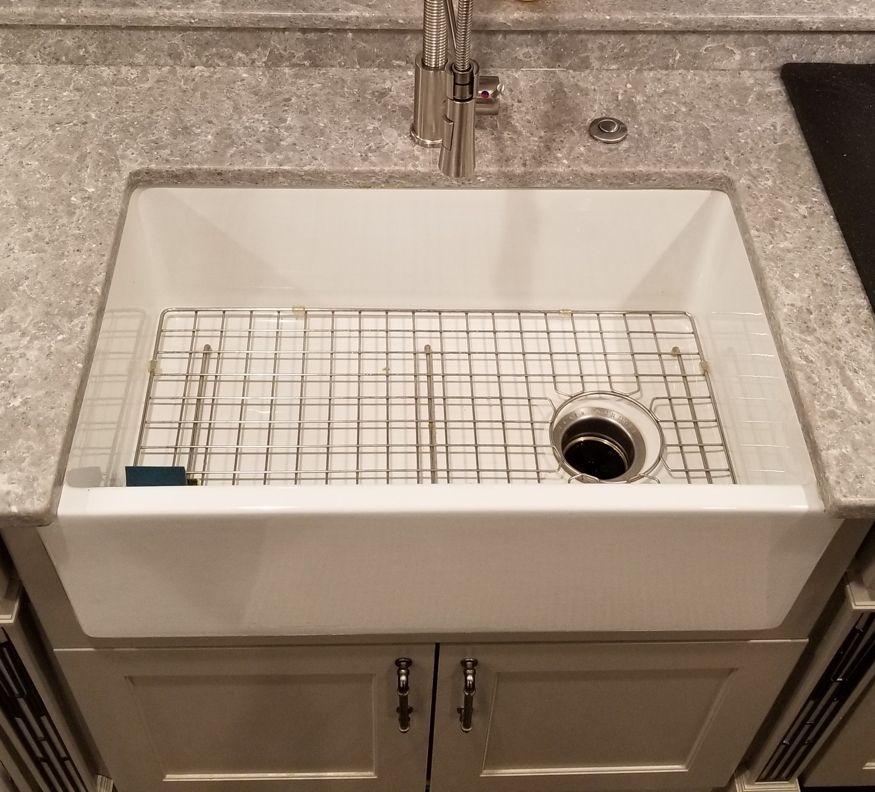 Apron-front farmhouse sink installed under a granite countertop