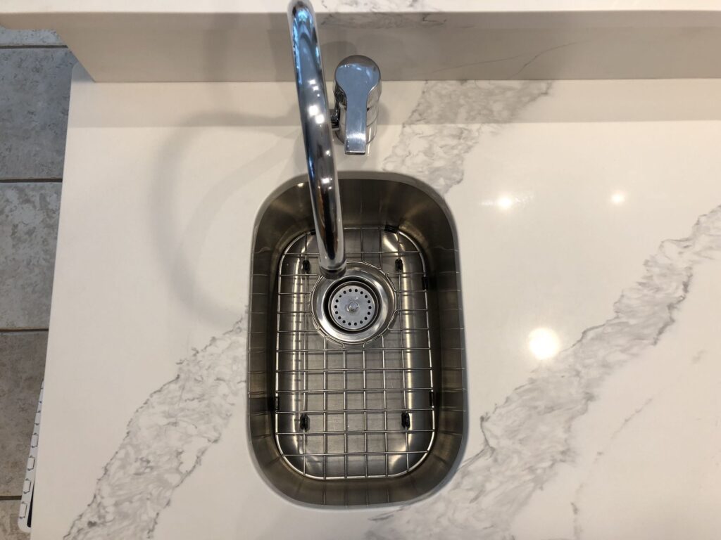Small undermount bar sink installed in a white quartz countertop