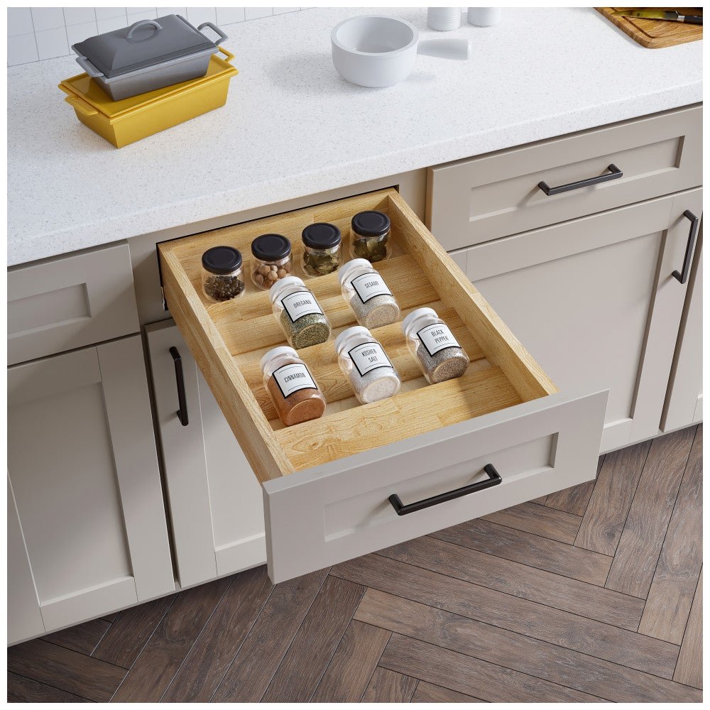 Spice drawer organizer with jars displayed on tiers in an open kitchen drawer