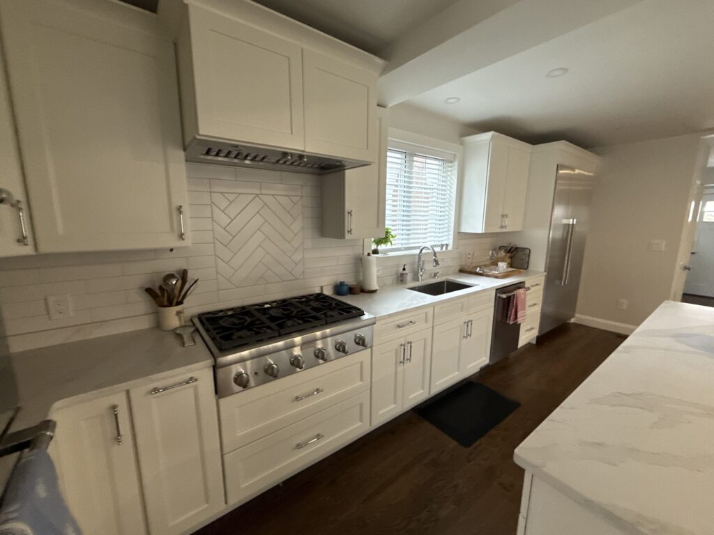Open kitchen with island, built-in refrigerator and windows over the sink – West Roxbury