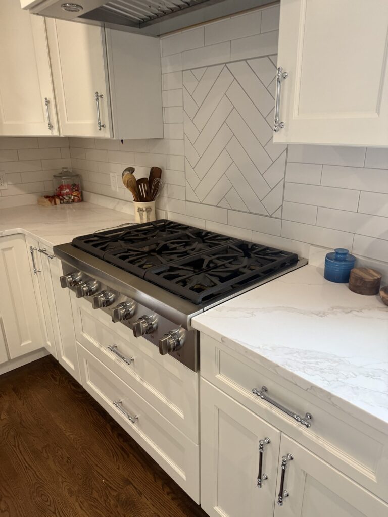 Professional gas cooktop with herringbone tile backsplash; all-plywood cabinet construction above dovetail hardwood soft-close drawers – West Roxbury