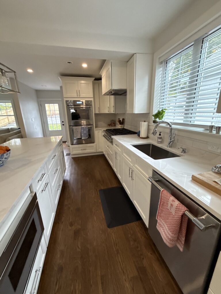 Double wall ovens, range and sink wall in white shaker cabinetry – West Roxbury