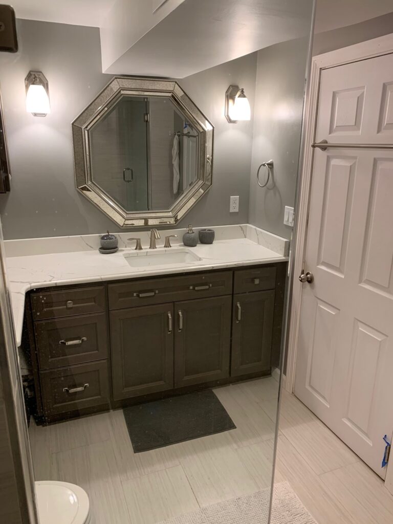 Basement bathroom vanity with light quartz top, undermount sink and octagon mirror – Randolph, MA