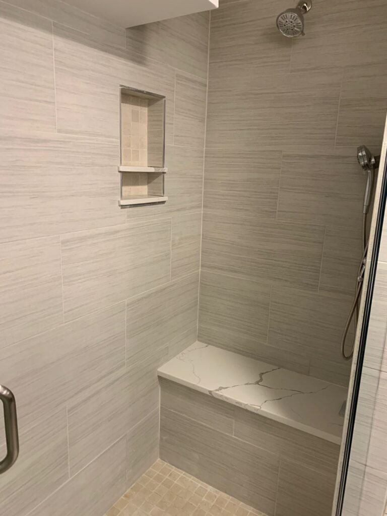 Tiled shower with quartz bench and built-in niches – Randolph basement bath