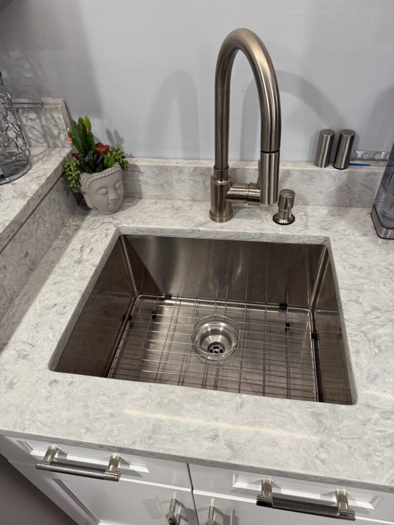 Stainless undermount sink with bottom grid in a light quartz countertop – Randolph